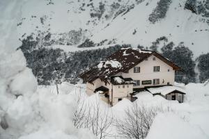 une maison recouverte de neige devant une montagne dans l'établissement Veranda Hotel, à Goudaouri