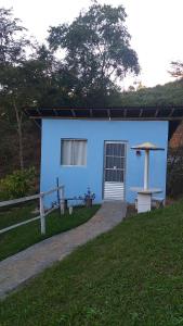 a blue house with a table and an umbrella at Chalé iglu joto in Conceição do Mato Dentro