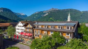 eine Luftansicht eines Gebäudes mit Bergen im Hintergrund in der Unterkunft Sonne Bezau - Familotel Bregenzerwald in Bezau