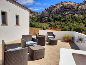 a patio with chairs and tables and a mountain at Lu Lisandru in Abbiadori