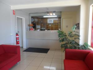 a waiting room with two red chairs and a counter at Liberty Plains Motor Inn in Sydney