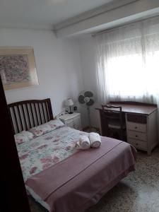 Un dormitorio con una cama y un escritorio y una ventana. en Anahouse, en Alcalá de Henares