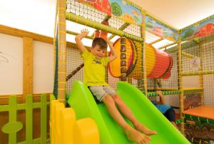 a young boy sliding down a slide at a playground at Àlia Bianca Active & Family Hotel in Andalo