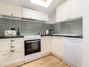 a kitchen with white cabinets and a sink and an oven at Kerslake Cottage in Bodmin