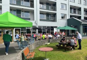 een groep mensen die aan tafels voor een gebouw zitten bij Atlantic Apartotel in Bundoran