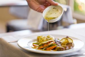 a person pouring sauce into a plate of food at Hotel Do Parque - Congress & SPA in Termas de Sao Pedro do Sul