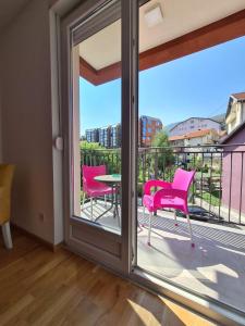 Habitación con balcón con mesa y sillas rosas. en Apartman Jelena Sokobanja en Soko Banja