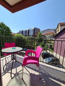 Duas cadeiras cor-de-rosa e uma mesa na varanda. em Apartman Jelena Sokobanja em Sokobanja