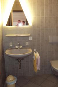 un uomo che scatta una foto di un bagno con lavandino di Auberge Restaurant Couronne a Beurnevésin