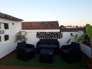 un patio avec des canapés et des plantes sur un mur blanc dans l'établissement La Mirada de La Judería, à Cordoue