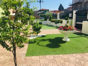 un pequeño jardín con un jarrón en la hierba en B&B La Dea Hestia, en Bosa