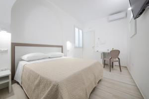 Habitación blanca con cama y escritorio en B&B SOLE en Torre San Giovanni Ugento