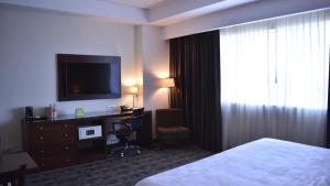 Habitación de hotel con cama, escritorio y TV. en Holiday Inn & Suites Plaza Mayor, an IHG Hotel, en León