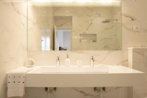 een witte badkamer met een wastafel en een spiegel bij Luxury apartment Mirage Split in Split