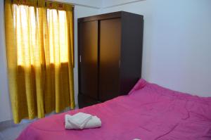 a bedroom with a bed with pink sheets and a cabinet at TAID in Esquel