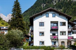 a large white building with a mountain in the background at Pramulin in Selva di Val Gardena