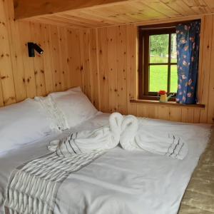 a large white bed in a wooden room with a window at Foxglove Accommodation in Craven Arms