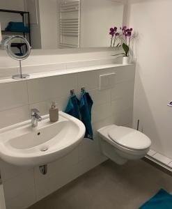 a white bathroom with a sink and a toilet at Glück am Meer in Glücksburg