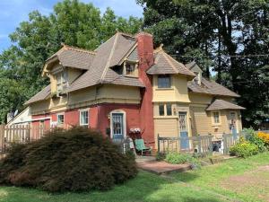 a large house with a roof in a yard at The Suite in a historic carriage house in Kennett Square