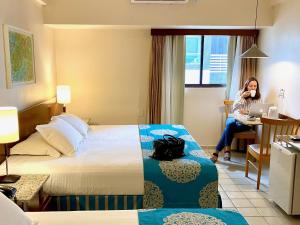 uma mulher sentada numa secretária num quarto de hotel em Kastel Manibu Recife - Boa Viagem no Recife