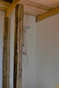 a bathroom with a shower with a wooden beam at Domek letniskowy TONKA in Świątki
