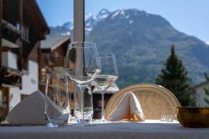 a table with wine glasses on a table with a view at Wellnesshotel Schweizerhof in Saas-Fee