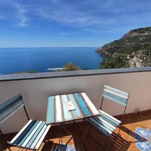 een tafel en stoelen op een balkon met uitzicht op de oceaan bij Torre Elisea in Minori