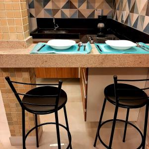 a kitchen with two stools at a kitchen counter at Apartamento Mania in Vitória +25 photos