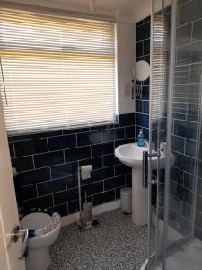 Baño de azulejos azules con aseo y lavamanos en Sunrise 77 Sandown Bay Holiday Centre Generous Ferry Saving! en Sandown