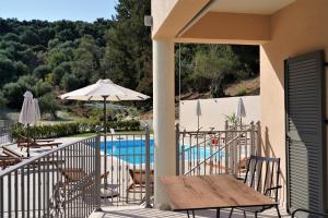 a balcony with a table and an umbrella and a pool at MERAVIGLIA in Parga