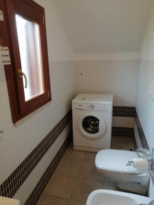 a bathroom with a washing machine and a toilet at Appartamento al centro di Budoni in Budoni +7 photos
