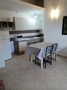 uma cozinha com uma mesa e uma cozinha com armários brancos em Appartamento al centro di Budoni em Budoni