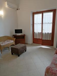 uma sala de estar com uma televisão, uma cadeira e uma secretária em Appartamento al centro di Budoni em Budoni