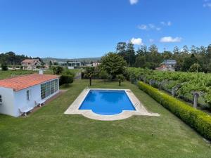 uma vista sobre um quintal com uma piscina e uma vinha em Tranquilidad con piscina en Casa Nantes en Sanxenxo em Sanxenxo
