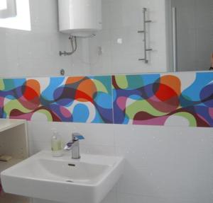 a bathroom with a sink and a colorful wall at Mala vila Punta Skala in Petrcane