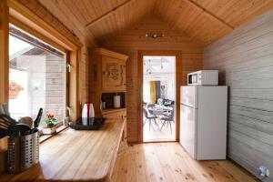 a kitchen with a refrigerator and a dining room at Mežmadaras in Kuldīga