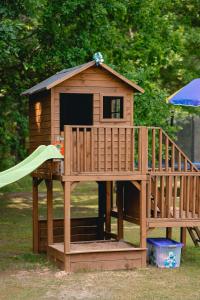 a small wooden play house with a slide at Mežmadaras in Kuldīga +9 photos