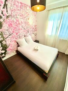 a bedroom with a white bed with a floral wall at Evasion dépaysante en bord de Garonne in Toulouse