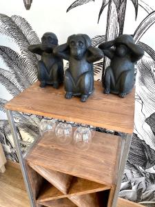 three monkey statues sitting on a table with wine glasses at Evasion dépaysante en bord de Garonne in Toulouse
