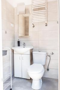 a white bathroom with a toilet and a sink at Apartament Piastowska in Olsztyn