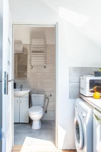 a bathroom with a toilet and a washing machine at Apartament Piastowska in Olsztyn