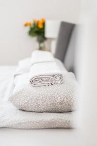 a stack of white towels sitting on a bed at Apartament Piastowska in Olsztyn
