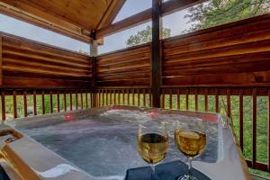 zwei Gläser Wein in einem Whirlpool auf einer Terrasse in der Unterkunft A Cozy Mountain Hideaway - 1 Bedrooms, 1 Baths, Sleeps 4 cabin in Sevierville