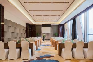 a conference room with tables and chairs and a projection screen at Wanda Realm Yinchuan in Yinchuan