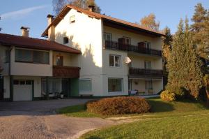 a large white house with balconies and a driveway at Sonnhügel Apartments - Ferienwohnungen in Faak am See