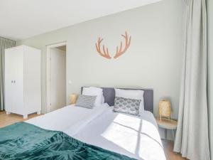 um quarto com uma cama grande com lençóis brancos e almofadas em Luxury holiday home in Harderwijk with a jacuzzi em Stadsdennen