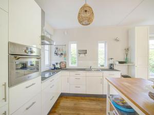 uma cozinha com armários brancos e uma mesa de madeira em Luxury holiday home in Harderwijk with a jacuzzi em Stadsdennen