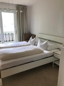 a bedroom with a large white bed with a window at Sonnhügel Apartments - Ferienwohnungen in Faak am See