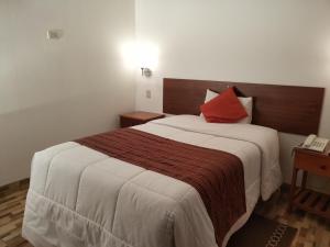 Habitación de hotel con cama grande y almohada roja en Viandina Machupicchu en Machu Picchu