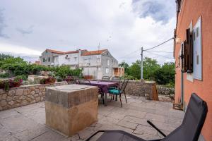 a patio with a table and chairs and a stone wall at Apartment Jurasić in Orlec